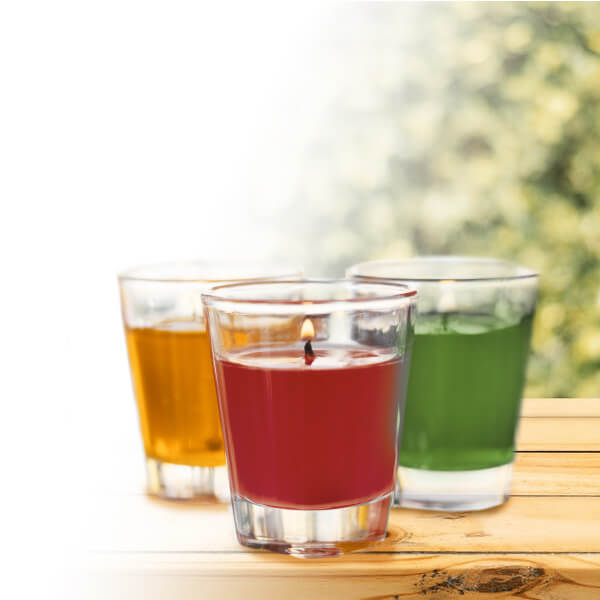 Velas perfumadas decorativas em copos de vidro coloridos em mesa de madeira ao ar livre